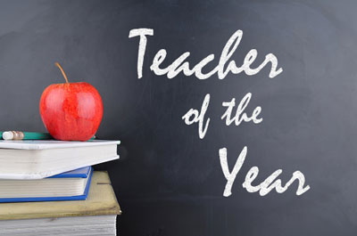 Teacher of the year written on chalkboard with books and apple