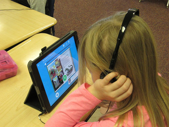 Student reading and listening to story on tablet