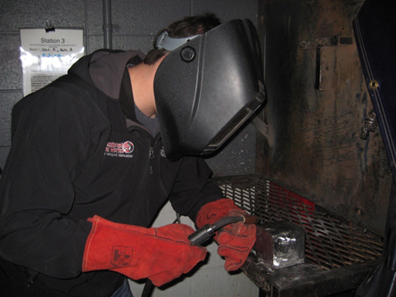 Photo of student welding. Caption: A first-year industrial technology student works on a welding project.