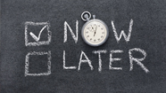 stock photo of chalkboard with Now and Later written on it. Check mark by Now