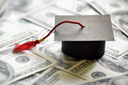 Stock photo of small graduation cap on top of cash.
