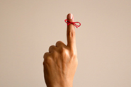 stock photo of red string tied around finger